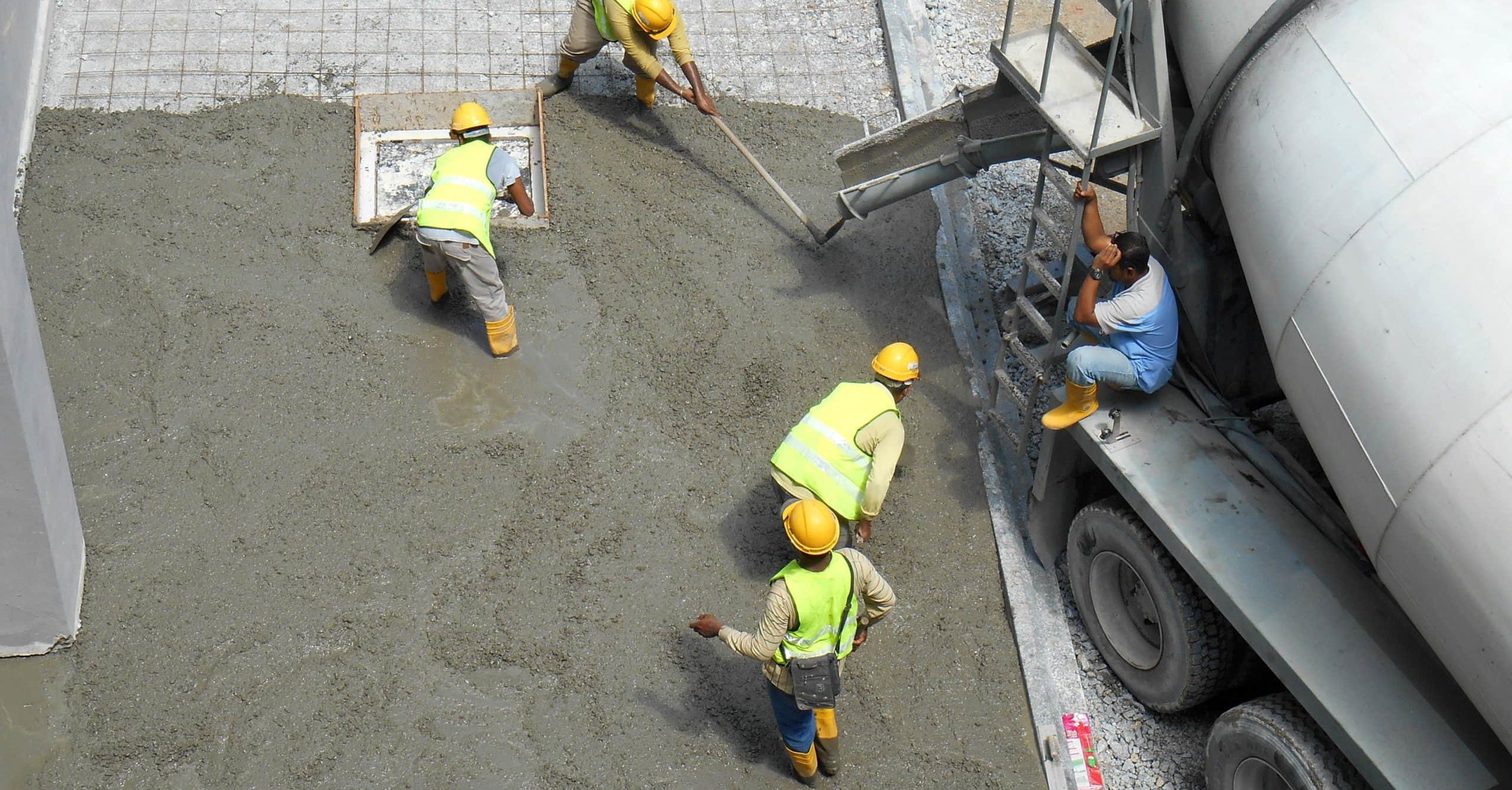 Construction workers leveling wet concrete has been poured. They also use a vibrator machine in this work.
